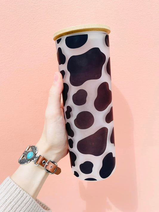 This black and white cow print-frosted glass tumbler is an ideal summertime accessory, complete with a plastic straw for drinking icy beverages.